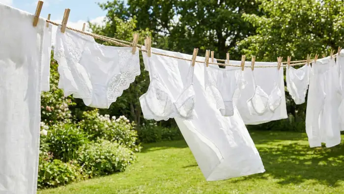 Strahlend weiße Wäsche auf der Leine. Dessous mit weißer Spitze, andere weiße Wäsche, kein bisschen vergraut, strahlend weiß
